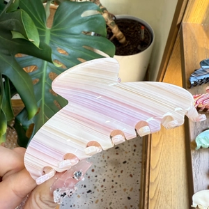Close-up of a pink and white marble acetate hair claw clip with wavy edges and glossy finish
