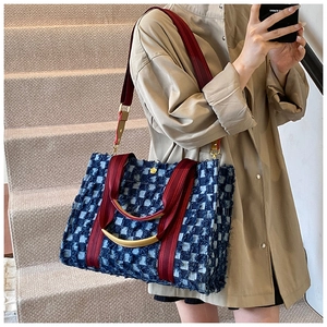 Blue and white plaid tweed tote bag with red straps worn with a khaki trench coat