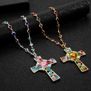Close-up of layered cross necklaces with colorful rhinestones in gold and silver finish