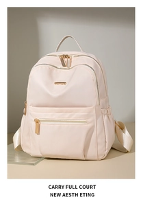 Close-up of beige nylon backpack showing premium gold zippers and smooth fabric texture