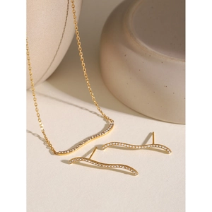 Macro detail of wave-shaped 18k gold-plated necklace and earrings set with white rhinestones