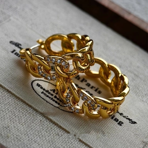 Golden link chain hoop earrings with sparkling zircon inlay on vintage linen backdrop