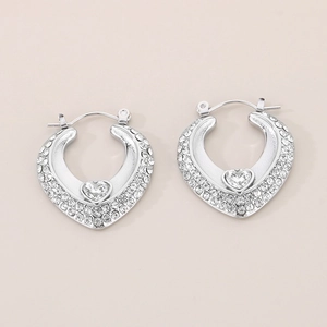 Gros plan sur boucles d'oreilles cœur en argent serties de cristaux et pierre centrale