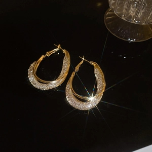 Macro detail of gold double hoop earrings featuring inner band paved with sparkling rhinestones
