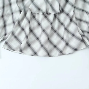 Fashionable black and white plaid off-shoulder blouse with ruffled hem and thin fabric
