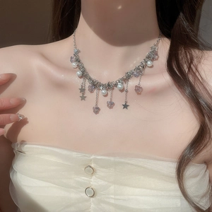 Détail de breloques papillon et étoile sur un collier en argent avec des perles