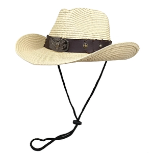 Detail of vintage straw cowboy hat featuring a metal bull head emblem and leather band