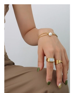 Detail of 18K gold-plated beaded bracelet with pearl and textured geometric rings