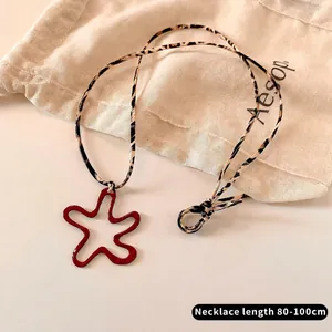 Detail of red star pendant with leopard print cord on a stylish sweater necklace