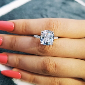 Close-up of a silver engagement ring with a large square stone worn by a female model