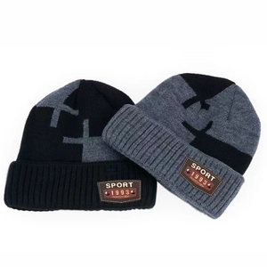 Détail d'un ensemble de bonnets tricotés avec motif croix et étiquette en cuir
