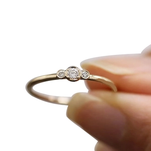 Elegant gold ring featuring three round zircons in a classic bezel setting on a slim band