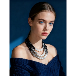 Three-layer faux pearl necklace featuring white, grey, and black beads on a navy sweater