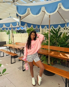 Outdoor view of pink sweatshirt with 'it's cool to be kind' text and zebra print shorts