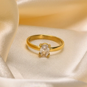 Detailed shot of an oval clear gemstone ring on elegant champagne satin fabric background