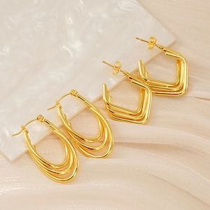 Detailed macro view of 18K gold layered oval and square stainless steel earrings on marble