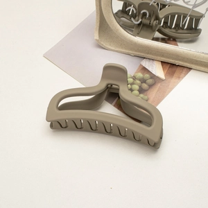 Macro detail of large matte olive green shark hair claw clip in a lifestyle setting