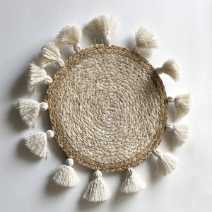 Dettaglio decorazione da parete boho in paglia intrecciata con nappe bianche e spirali
