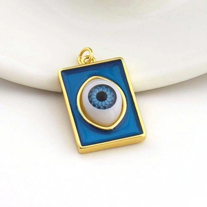 Macro view of a rectangular gold-plated evil eye pendant with blue enamel and eye detail