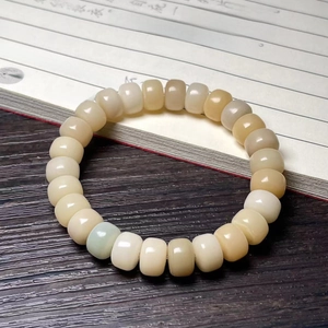 Macro shot of white bodhi root beads and carved cat paw charm on open book