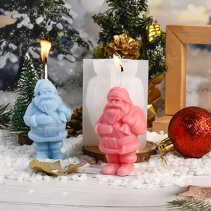 Weihnachtswichtel Silikonform mit fertigen rosa und blauen Kerzen im Winterschnee