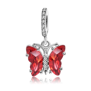 Macro shot of silver butterfly charm with faceted red crystals and clear stone inlay
