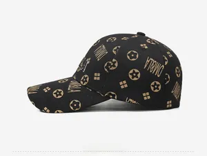Detail view of black baseball cap with golden embroidered monogram and star patterns