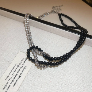 Dettaglio della collana Y2K con perle nere, cristalli e design a nodo intrecciato