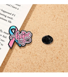 Nahaufnahme der rosa-blauen Emaille-Schleifenbrosche mit Hope-Text und Gummikupplung