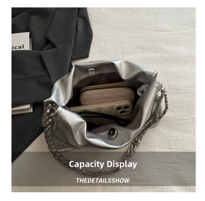 Interior capacity display of silver cloud bag holding smartphone, wallet and sunglasses