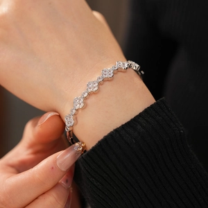Detail showing elegant silver clover bracelet with sparkling cubic zirconia on a black sleeve