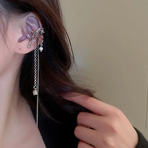 Gros plan d'un ear cuff argenté à pampilles avec perles et zircons sur l'oreille