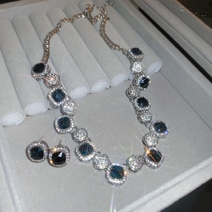 Detailed view of silver jewelry set with black gemstones and crystals in a box
