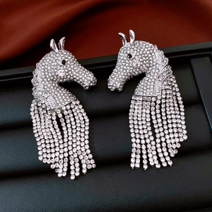 Detailed view of silver horse head earrings with crystal tassels on a black jewelry tray