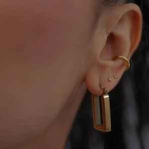 Minimalist golden stainless steel paperclip earrings and stud set worn by a female model