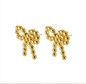 Detailed close-up of 18K gold beaded bow earrings with textured metallic finish