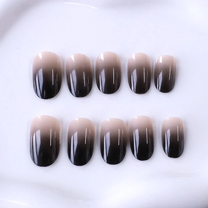 Short oval press-on nails featuring a glossy black to nude vertical gradient effect