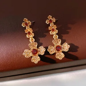 Vintage gold drop earrings with red gemstones and champagne crystals on leather background