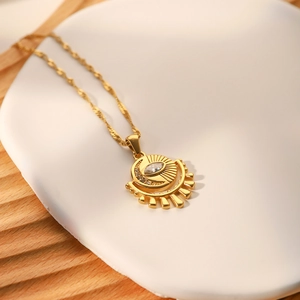 Vintage French gold evil eye necklace with zircon stones on a white ceramic plate