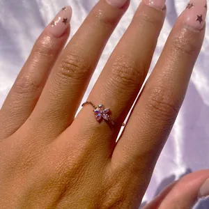Macro shot of rose gold wave ring featuring iridescent purple flower petals on model