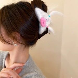 Detail of cute white plush monster hair claw clip with pink mouth on a girl's hairstyle
