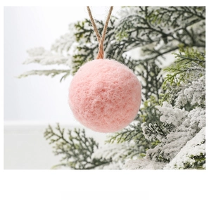 Detailed view of pink felt ball ornament with jute rope on snowy pine branches