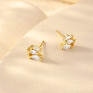 Close-up of gold stud earrings featuring three marquise-cut zircons in a fish shape