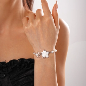 Elegante bracciale a fiori in argento con perle e petali bianchi indossato al polso