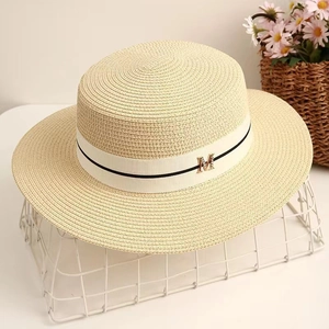 Détail d'un chapeau canotier en paille avec ruban blanc et ornement en métal M
