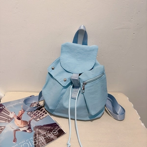 Detail view of the light blue nylon backpack showing the drawstring closure and side pockets