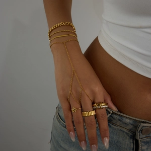 Detailed view of 18K gold hand chain and layered zircon rings on a model hand
