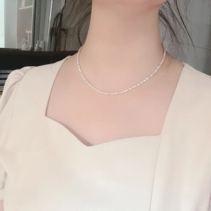 Detail shot of a minimalist silver choker necklace on model with shimmering crystal accents