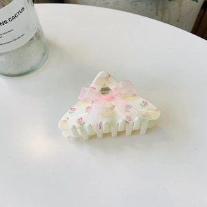 Detail of cream acrylic hair claw with floral duck print and pink ribbon bow