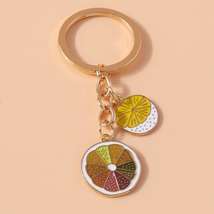 Close-up of golden keychain with enamel lemon and colorful fruit slice pendants